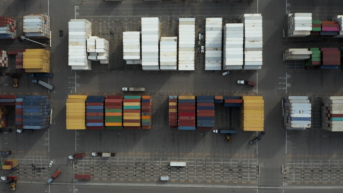 Flygvy över en containerterminal med organiserade rader av containrar.